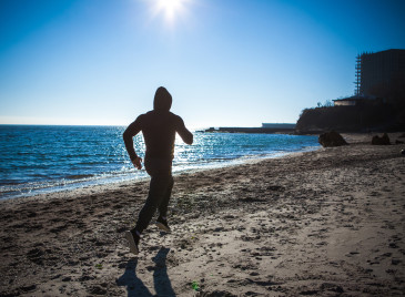 Running man jogging on beach.